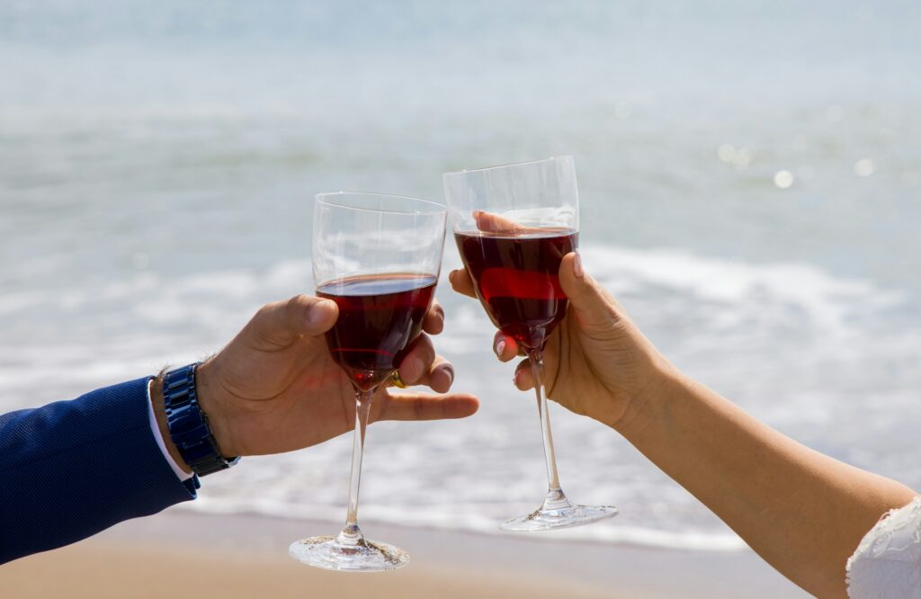 5 Tips For Choosing The Perfect Wine For Your Wedding Two people toasting with wine on beach.
