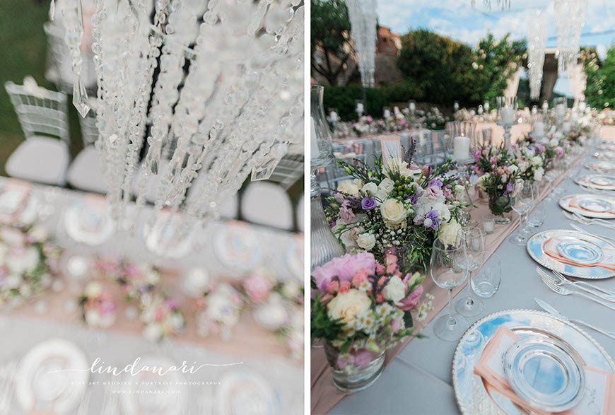 Sparkling crystal chandeliers hung over elegantly draped tables, with pink silk runners and silver chargers. Tea lights in small glasses sparkled along with a host of larger candles and more vases of beautiful flowers. Sparkling crystal chandeliers hung over elegantly draped tables, with pink silk runners and silver chargers. Tea lights in small glasses sparkled along with a host of larger candles and more vases of beautiful flowers.