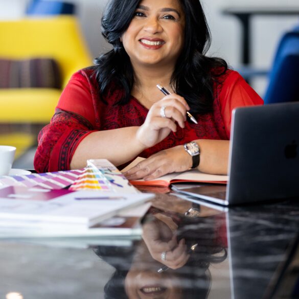 Smiling woman with laptop and colour swatches.