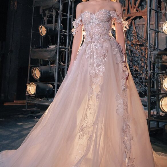 Elegant woman in detailed wedding gown on stage.