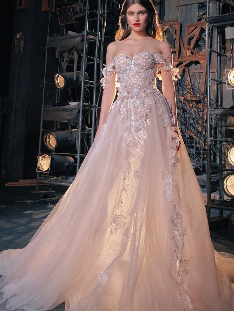 Elegant woman in detailed wedding gown on stage.