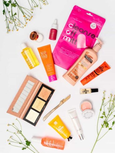 Assorted skincare products on white background with flowers.