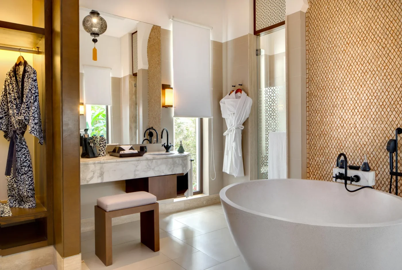 Luxurious modern bathroom with bathtub and robes.
