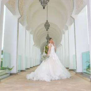 Bride posing in white dress in arched hallway.