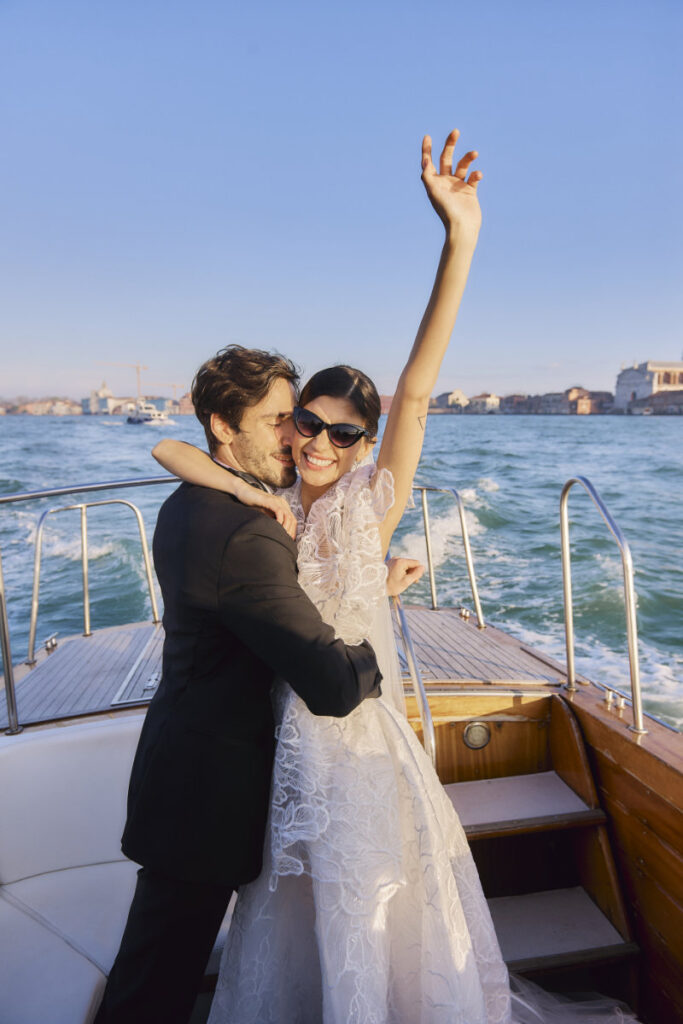 A Vision Of Venice Weddings Couple celebrating on boat in Venice, happy embrace.