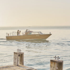 People on a wooden boat in serene waters.