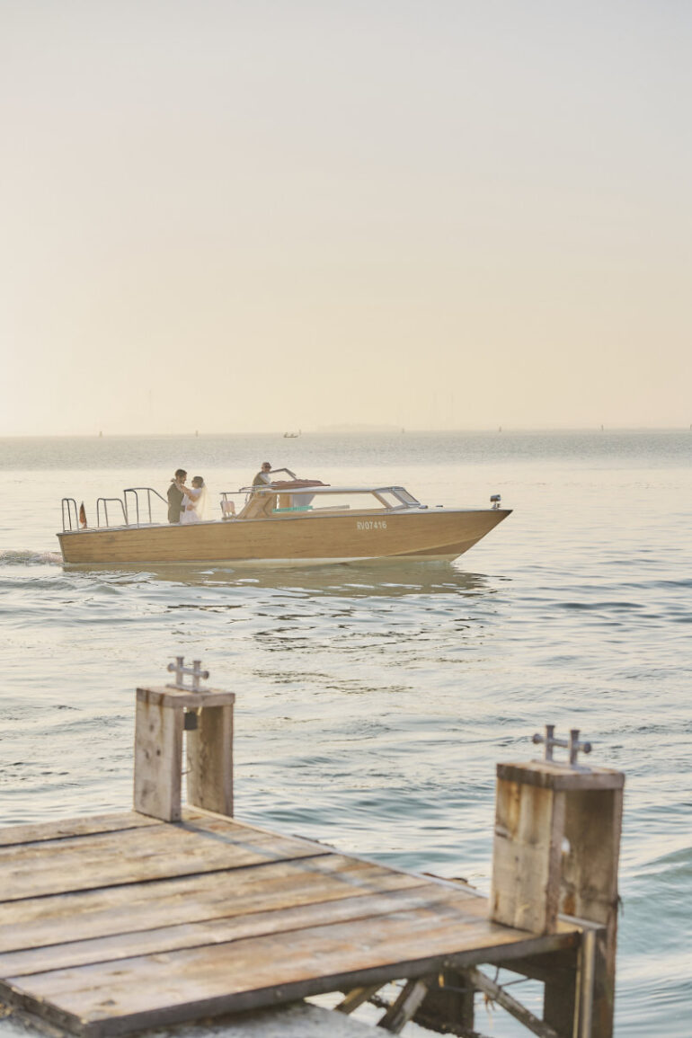 People on a wooden boat in serene waters.