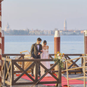 Couple walks on decorated pier by lake.