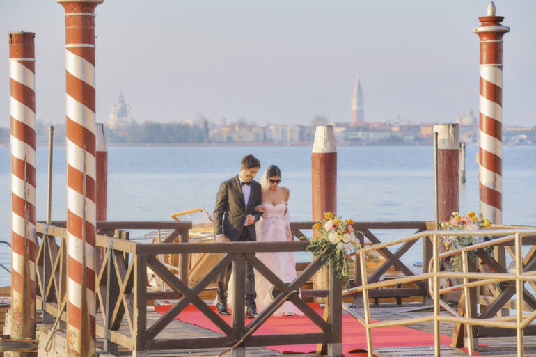 Couple walks on decorated pier by lake.