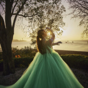 Person in green gown at sunset near lake