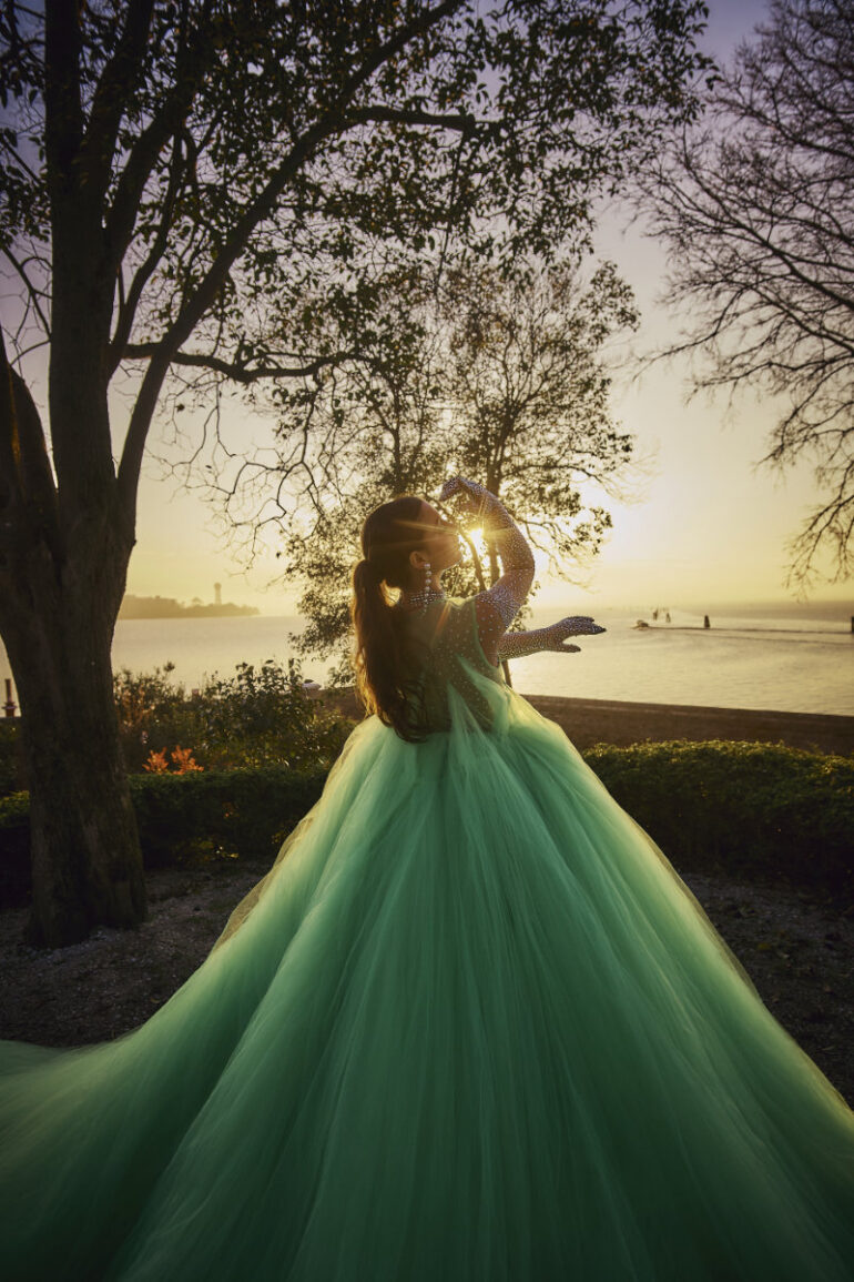 Person in green gown at sunset near lake