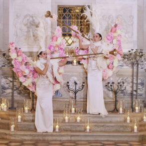 Two women with floral wings playing trumpets.