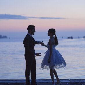 Dressed couple near water at sunset