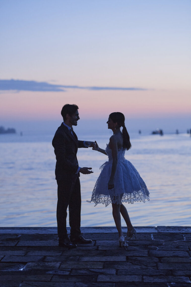 Dressed couple near water at sunset