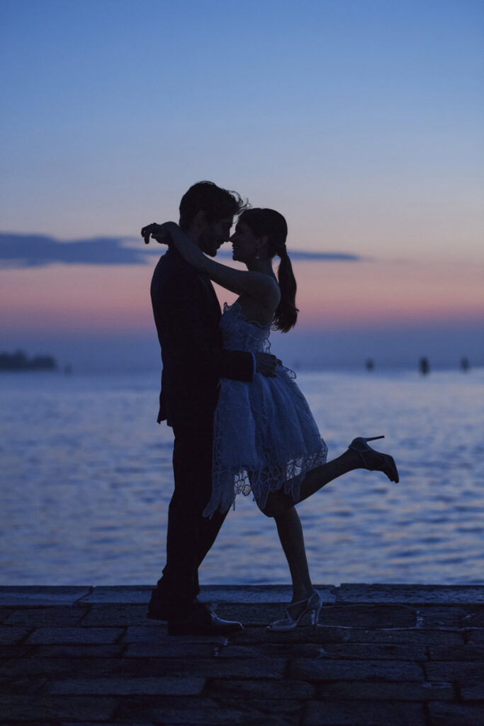 A Vision Of Venice Weddings Couple embracing romantically at sunset by the sea.