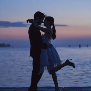 Romantic couple dancing by the seaside at sunset.