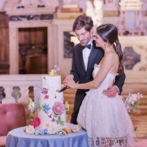 Couple cutting floral wedding cake in elegant venue.