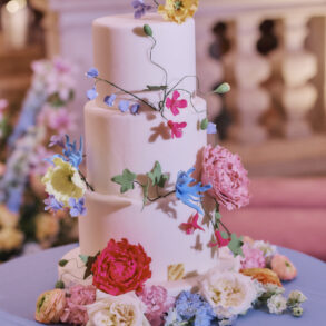 Three-tier wedding cake with colourful flowers decoration.