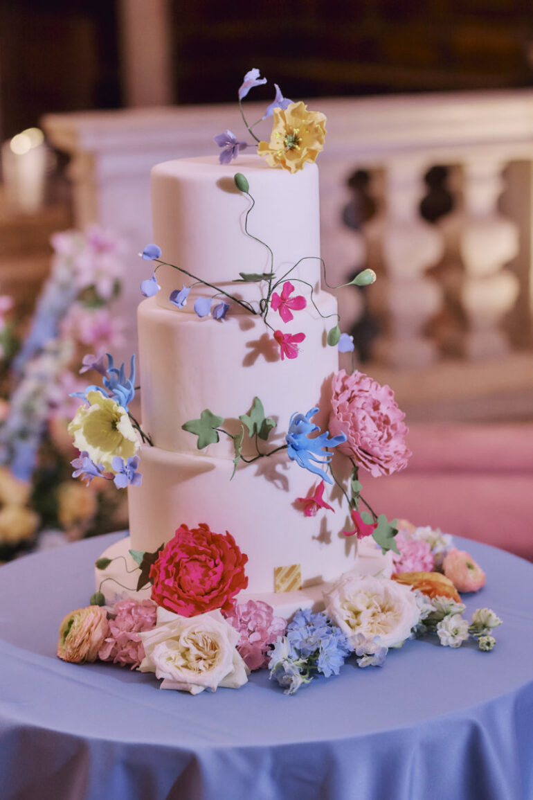 Three-tier wedding cake with colourful flowers decoration.