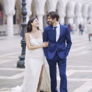 Bride and groom smiling, walking arm in arm.