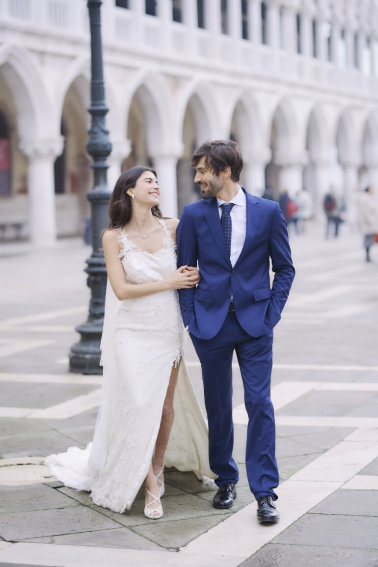 Bride and groom smiling, walking arm in arm.