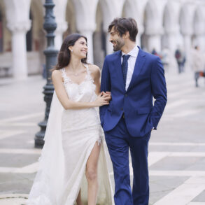 Bride and groom walking, smiling at each other.
