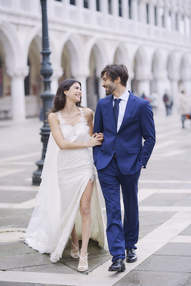 Bride and groom walking, smiling at each other.