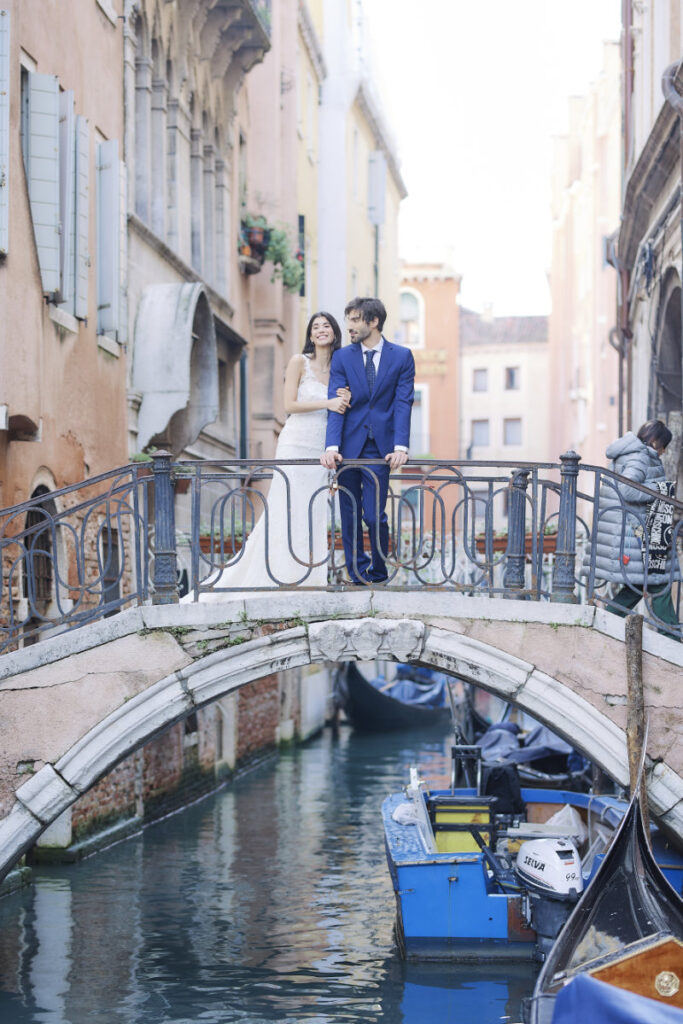 A Vision Of Venice Weddings Couple on Venice bridge over canal with gondolas.