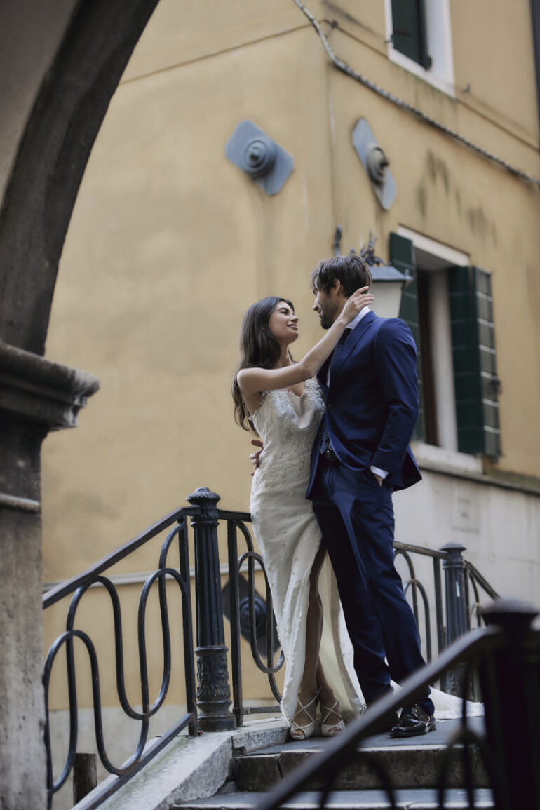 Couple embracing on a staircase in wedding attire.