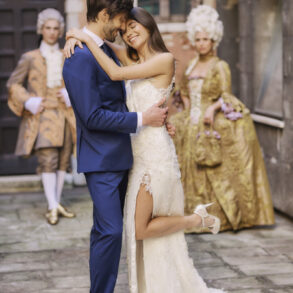 Bride and groom embrace in historical costumes.