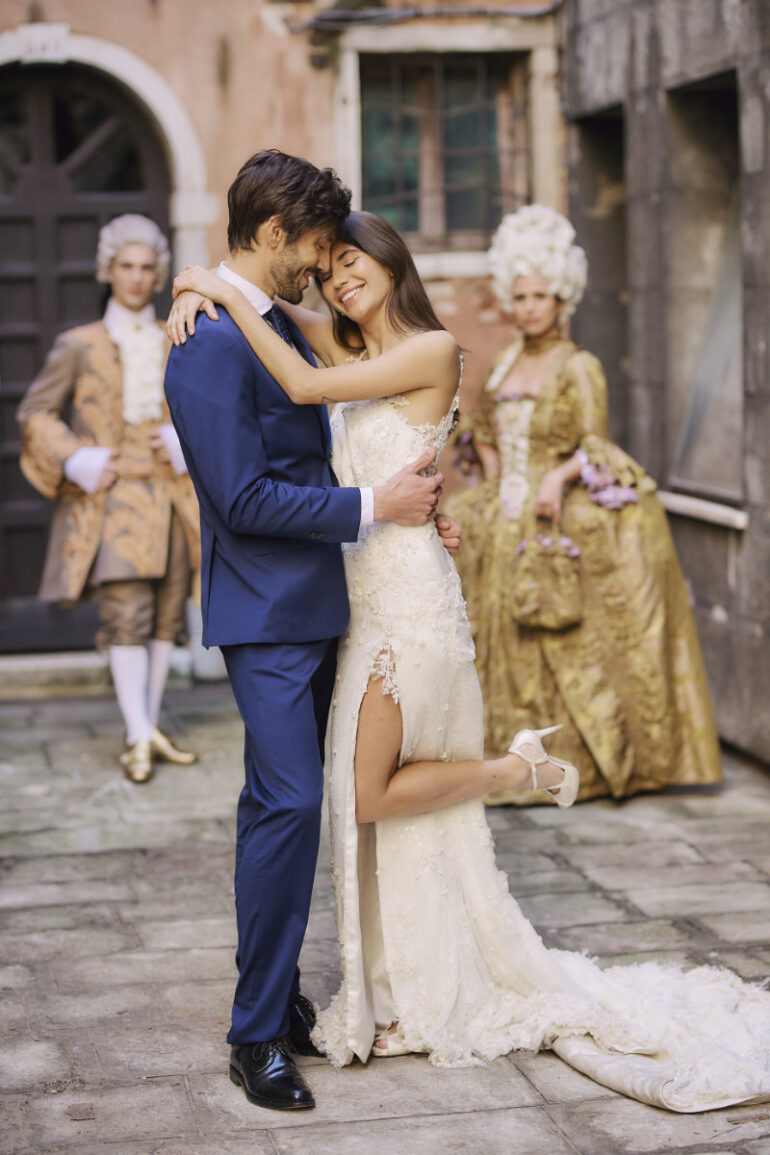 Bride and groom embrace in historical costumes.