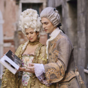 Couple in historical costumes reading a book.