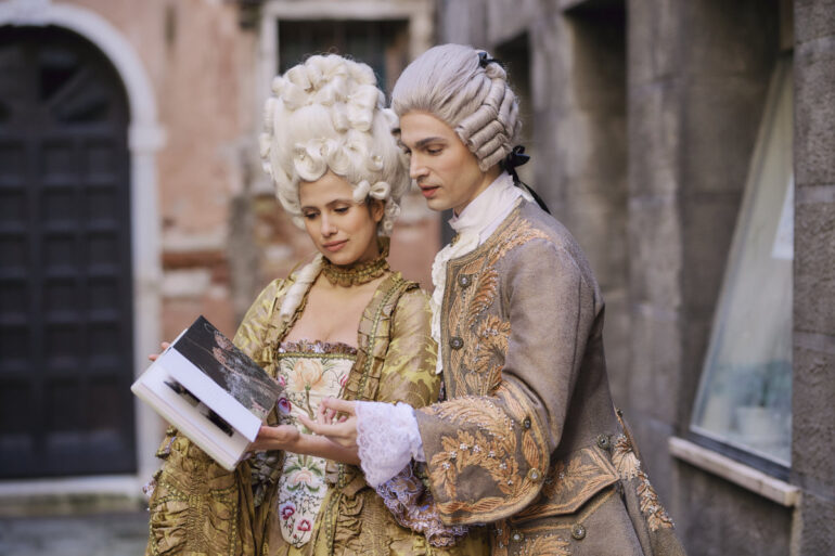 Couple in historical costumes reading a book.