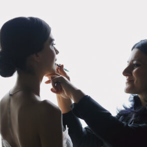 Makeup artist applying lipstick to bride.