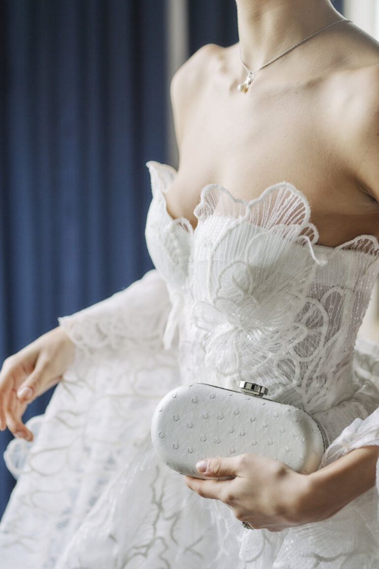 Bride holding clutch in lace wedding dress.