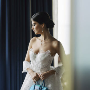 Bride holding blue handbag in white wedding dress.