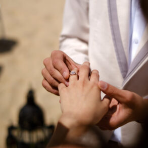 Man placing ring on woman's hand.