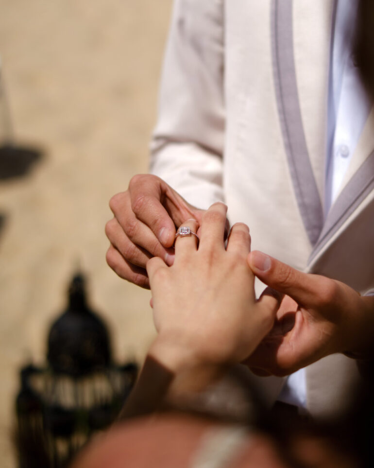 Man placing ring on woman's hand.