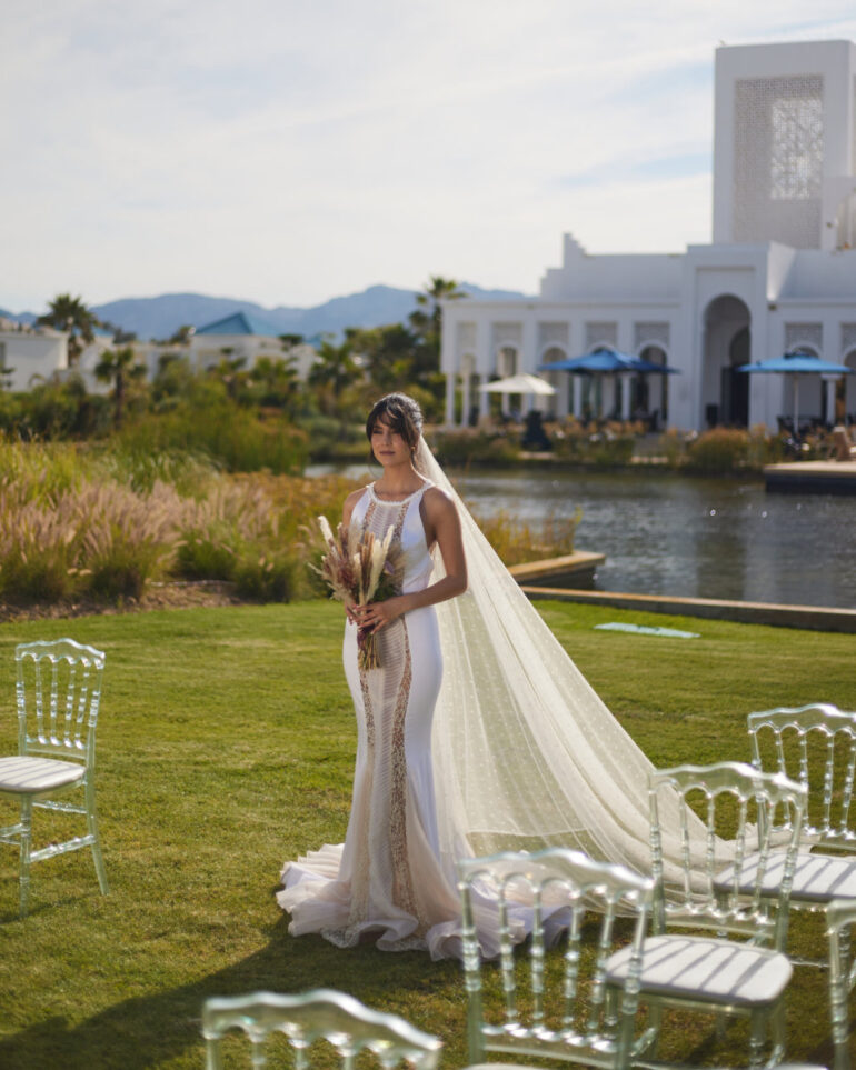 Bride in wedding dress outdoors by a pond.