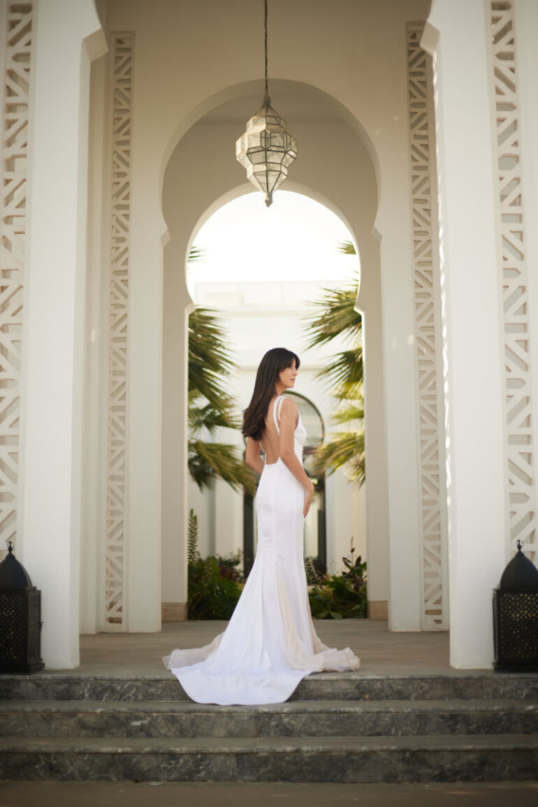 Woman in white dress in arched hallway