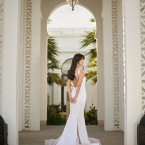 Woman in white dress standing in ornate archway.
