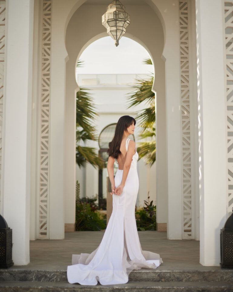 Woman in white dress standing in ornate archway.