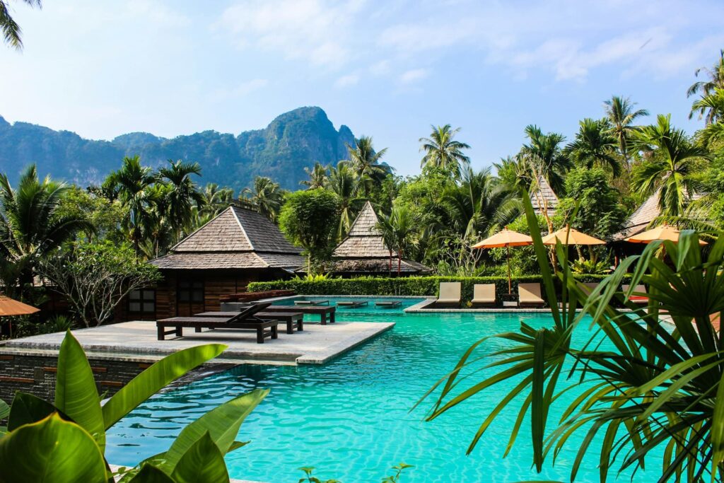 Top 20 Luxury Hotel Groups Tropical resort pool with mountains and trees.