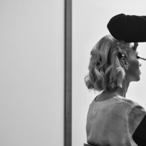 Woman getting makeup applied, black and white photo.