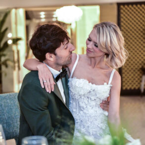 Bride and groom embracing on wedding day indoors.