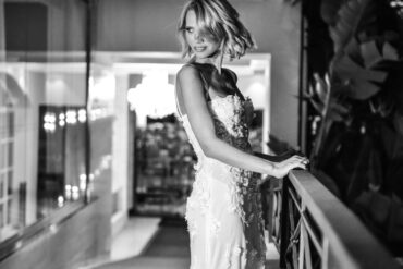 Woman in elegant lace dress, balcony at night.