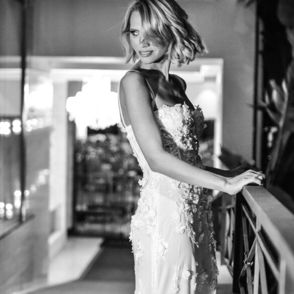 Woman in elegant lace dress, balcony at night.