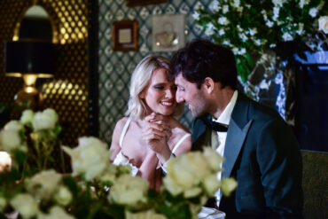 Couple holding hands, smiling at dinner table.