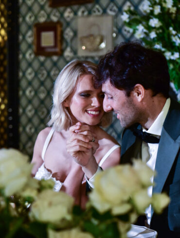 Couple holding hands, smiling at dinner table.