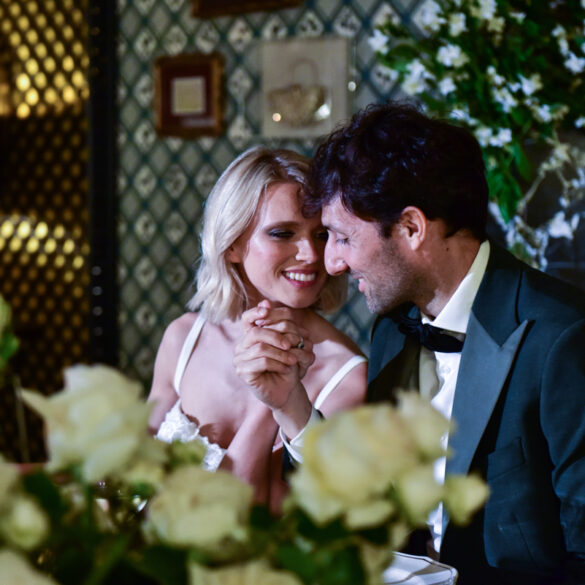 Couple holding hands, smiling at dinner table.